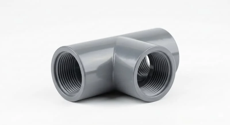 Chụp cận cảnh chi tiết cấu tạo một tê ống nước uPVC (tê chữ T) màu xám, đặt trên nền trắng tinh khiết.